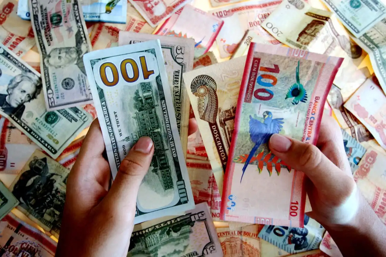 Bolivian banknotes and US dollars on a table in La Paz as Bolivia abandons its 15-year dollar peg and moves to a flexible exchange rate