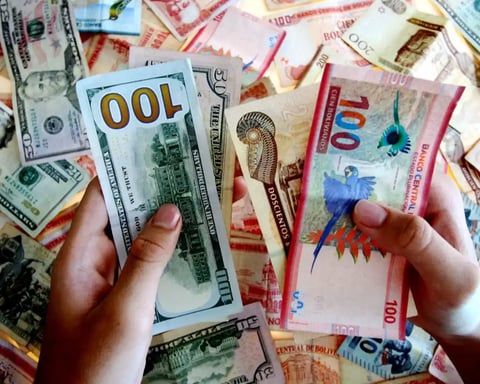 Bolivian banknotes and US dollars on a table in La Paz as Bolivia abandons its 15-year dollar peg and moves to a flexible exchange rate