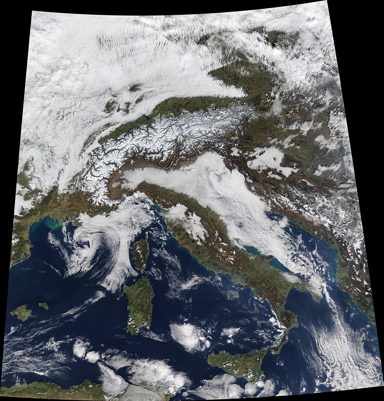 NASA MODIS Terra satellite image showing snow cover and low clouds around the European Alps