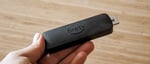 Amazon Fire TV Stick 4K Select streaming device held in hand showing compact HDMI dongle design