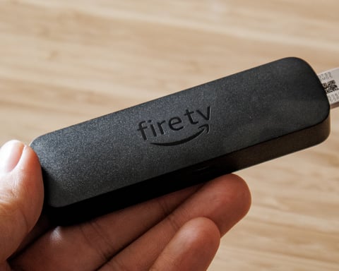 Amazon Fire TV Stick 4K Select streaming device held in hand showing compact HDMI dongle design