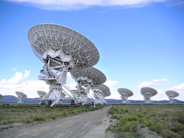 Dishes of a large radio telescope array against a desert sky