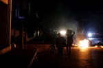 Residents walk past burning rubbish during protests over power cuts in Cuba