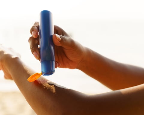 A person applies sunscreen before sun exposure