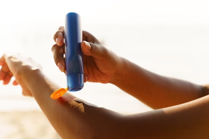 A person applies sunscreen before sun exposure