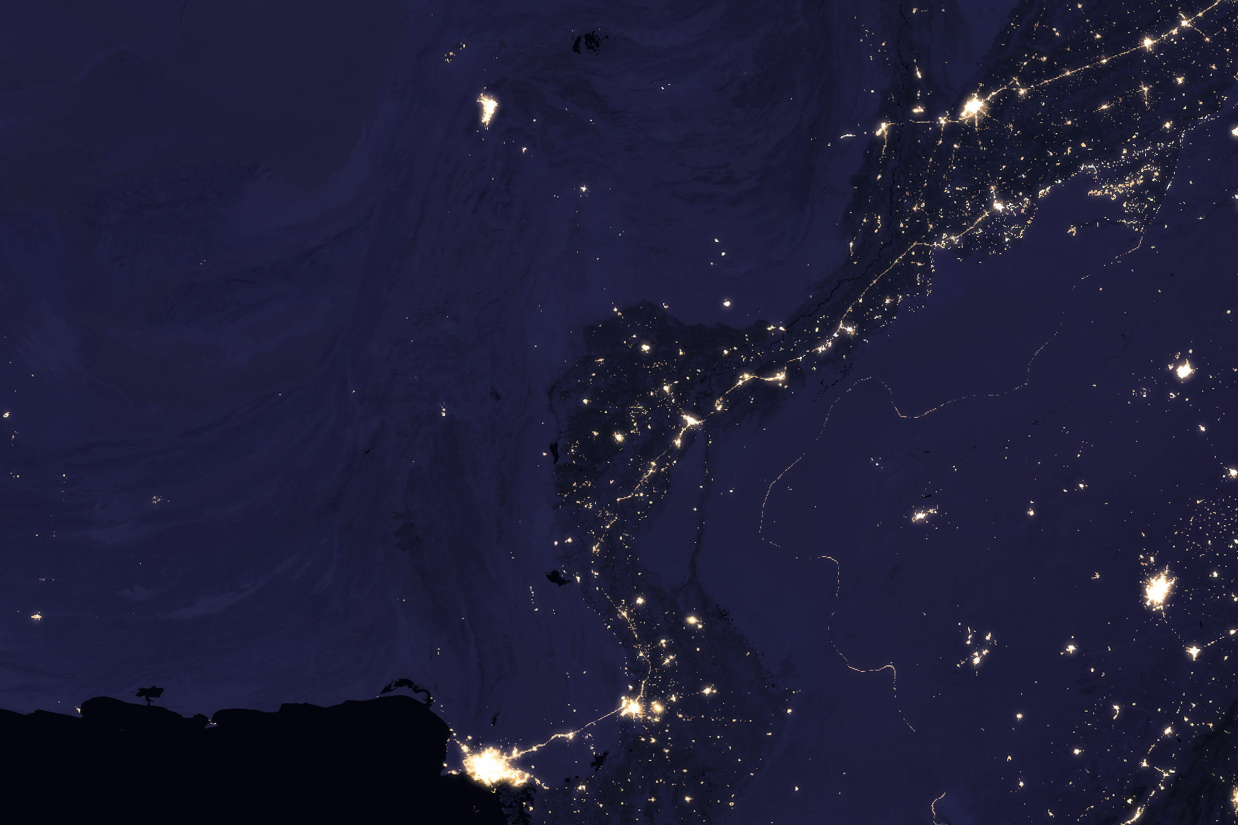 NASA VIIRS satellite image showing the Indus River basin in Pakistan at night with the sinuous shape of the river outlined by the lights of cities Lahore Multan Sukkur and Karachi against the darker desert and mountain landscape