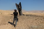 An Israeli settler inspects part of an Iranian missile protruding from the ground in the occupied West Bank June 8 2026