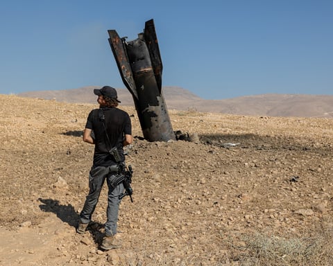 An Israeli settler inspects part of an Iranian missile protruding from the ground in the occupied West Bank June 8 2026