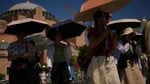 Tourists use umbrellas to shield themselves from intense sun outside Istanbul's Hagia Sophia during a summer 2025 heatwave