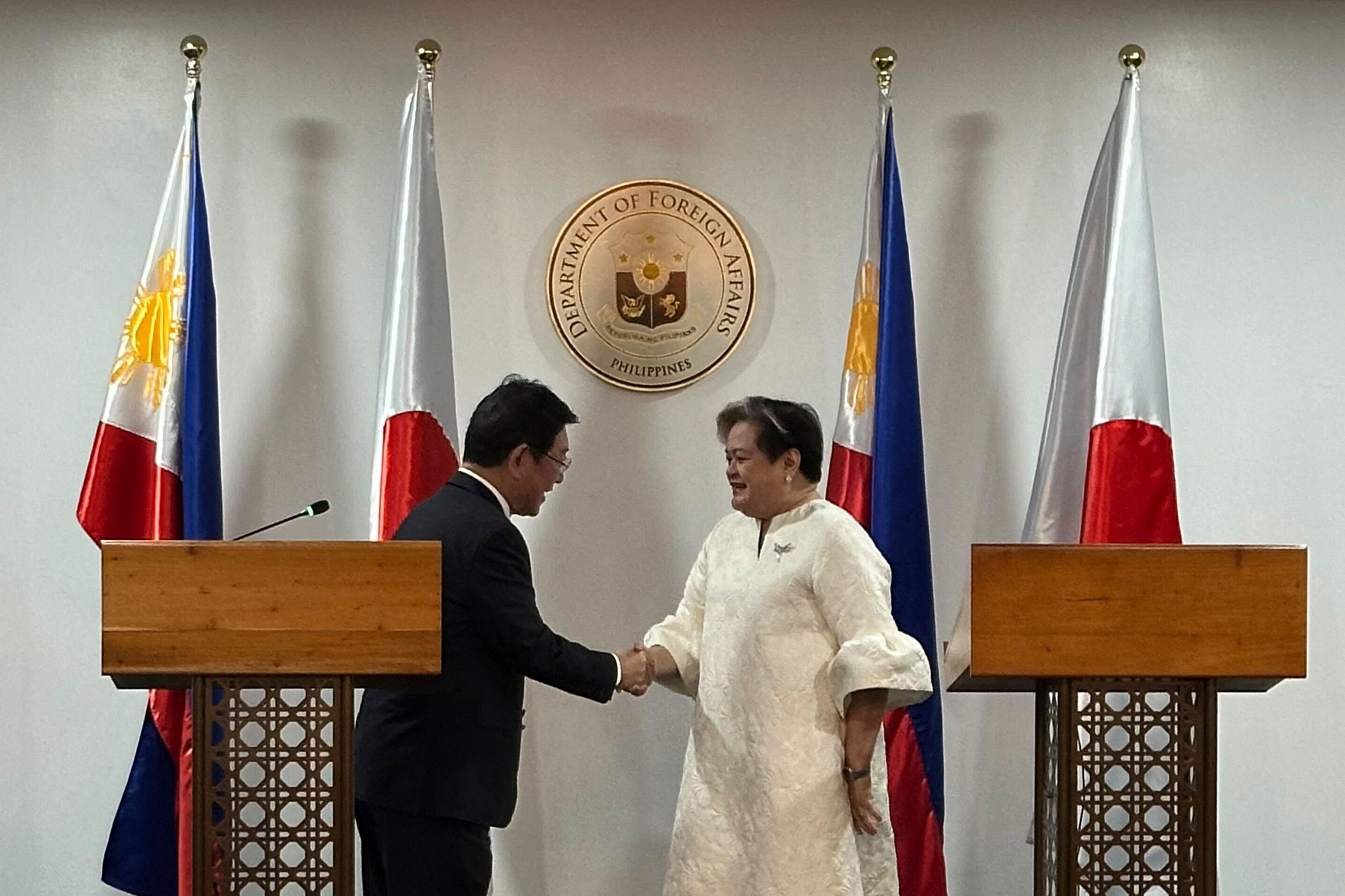 Japanese Foreign Minister Toshimitsu Motegi and Philippine Foreign Secretary Theresa Lazaro shake hands in Manila