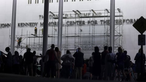Workers on scaffolding remove lettering of Donald Trump's name from the Kennedy Center facade