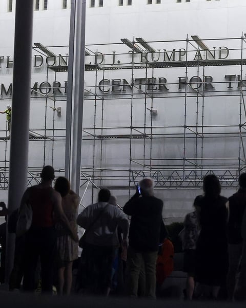 Workers on scaffolding remove lettering of Donald Trump's name from the Kennedy Center facade