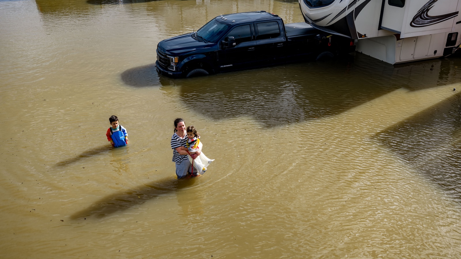 People wade through a recreational vehicle park flooded by a king tide near Corte Madera in Marin County, California