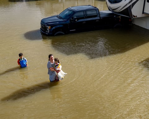 People wade through a recreational vehicle park flooded by a king tide near Corte Madera in Marin County, California