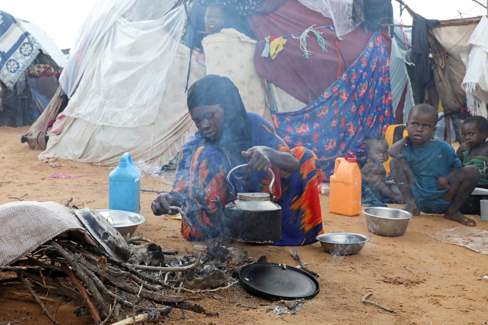 An internally displaced woman prepares breakfast outside a makeshift shelter in the Kahda district of Mogadishu, Somalia, as war-driven prices push families into hunger