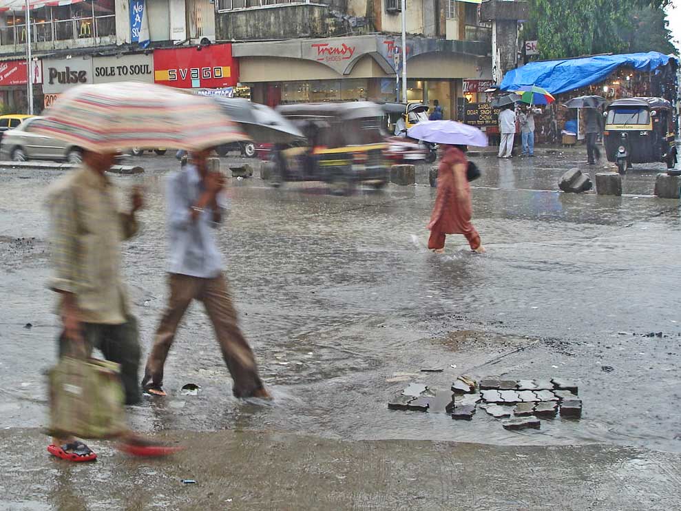 A Mumbai street under monsoon rain and grey skies