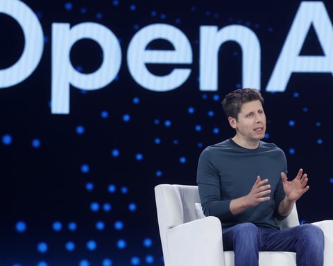 OpenAI chief executive Sam Altman seated on stage in front of a large OpenAI logo