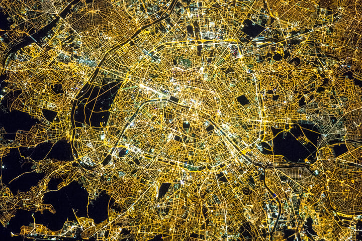 NASA astronaut photograph of Paris at night showing the Seine River as a thin black line with the bright Avenue des Champs Elysees and the radial street pattern around the Arc de Triomphe