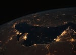 NASA astronaut photograph from the International Space Station of the Persian Gulf at night with the cities of Tehran, Dubai, Doha, Riyadh, Bahrain, and Kuwait City visible as bright clusters along the shoreline