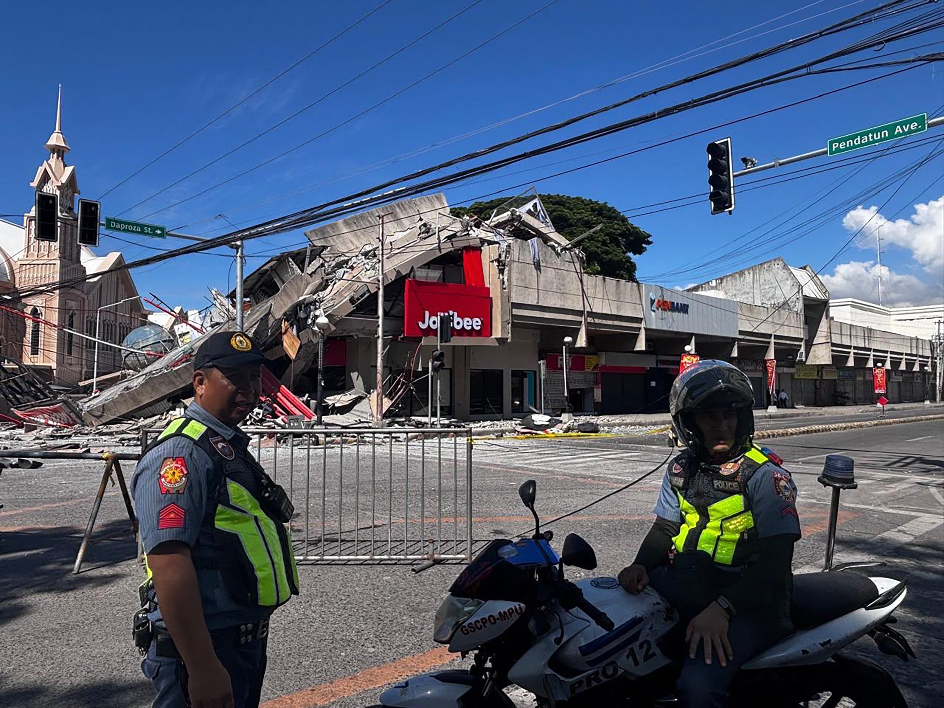 Police gather in front of a collapsed building after a magnitude 7.8 earthquake in General Santos, Philippines