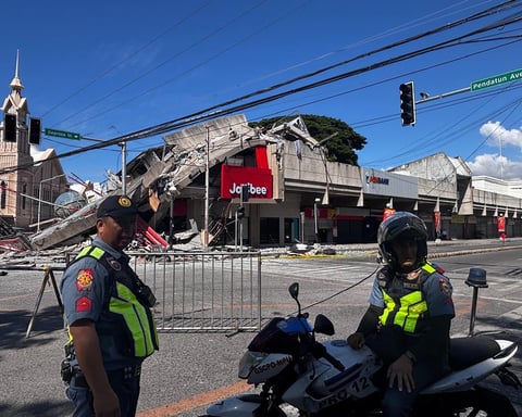 Police gather in front of a collapsed building after a magnitude 7.8 earthquake in General Santos, Philippines