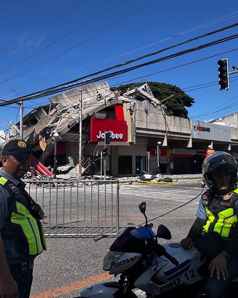 Police gather in front of a collapsed building after a magnitude 7.8 earthquake in General Santos, Philippines