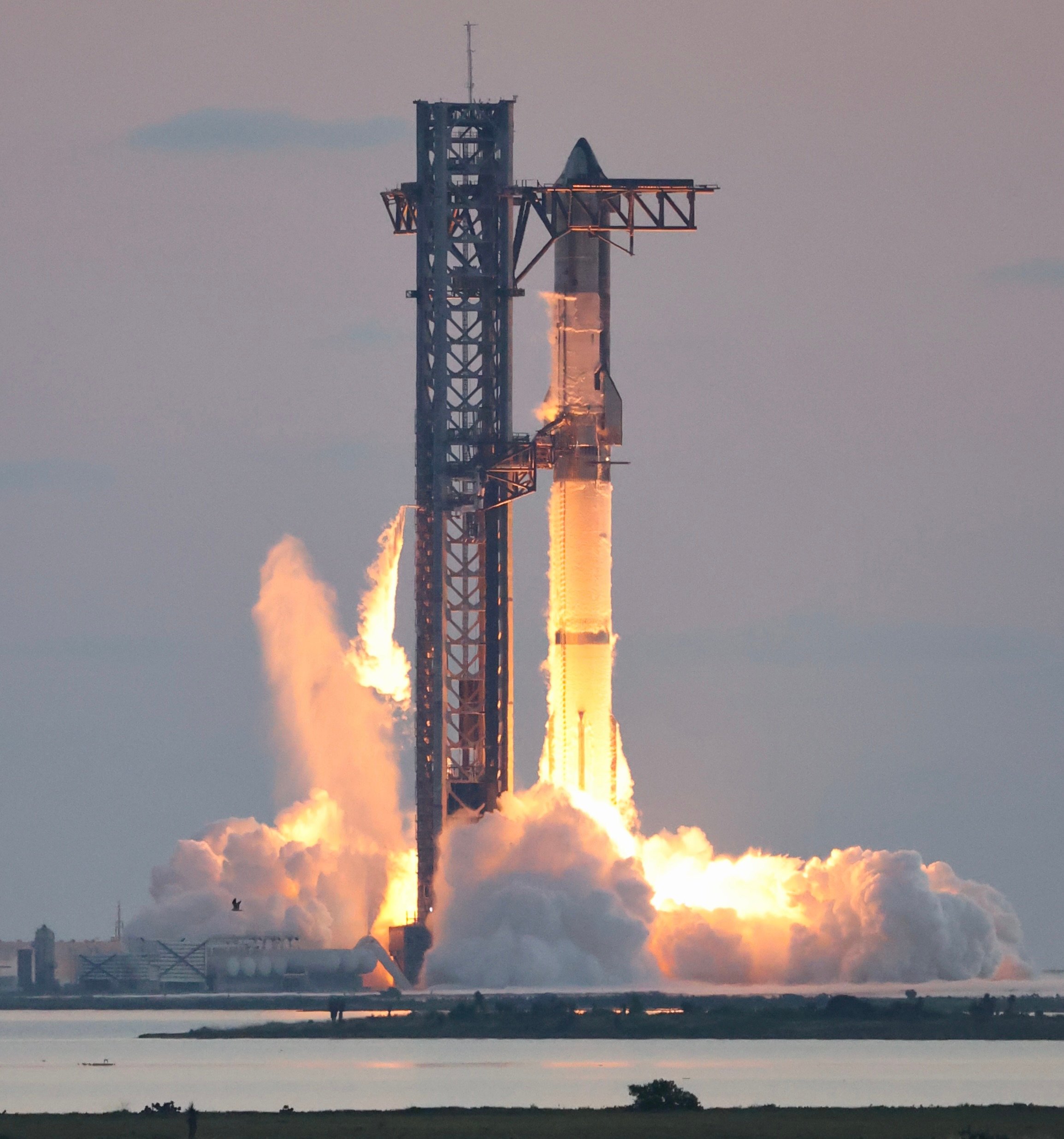 SpaceX's Starship rocket igniting its engines at liftoff in a cloud of flame and exhaust