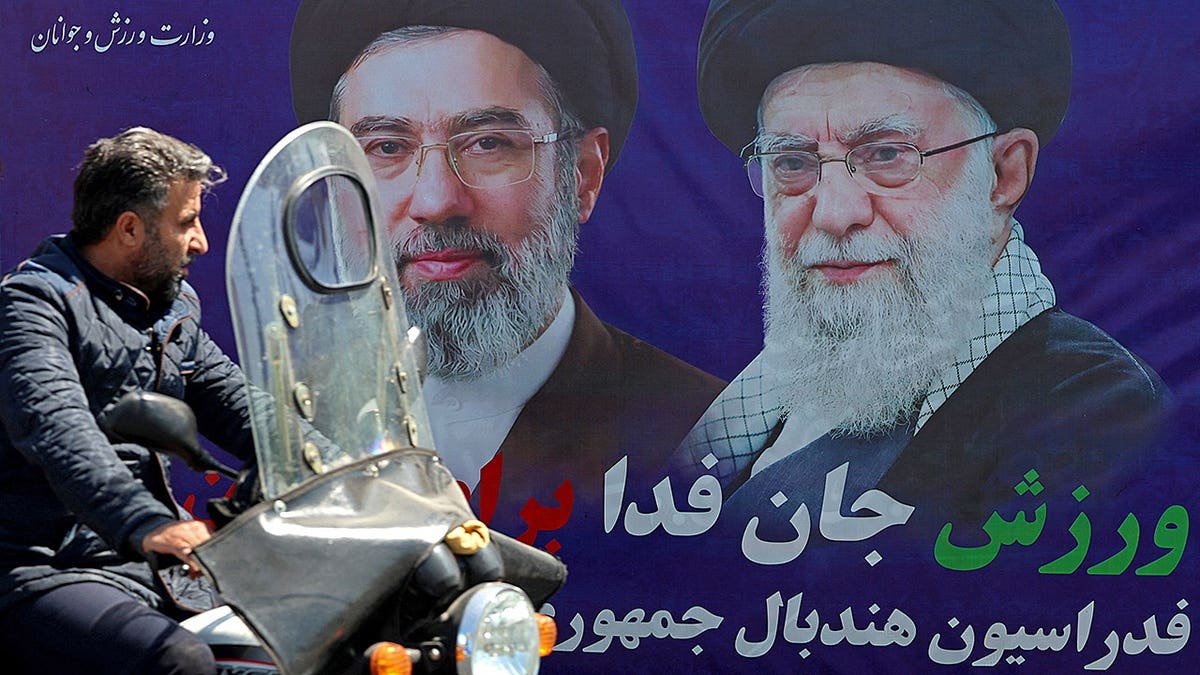 A motorist passes a banner depicting the late Ali Khamenei in Tehran ahead of the US-Iran memorandum signing