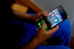 A high school student displays social media apps on a phone as Britain weighs a ban for under-16s