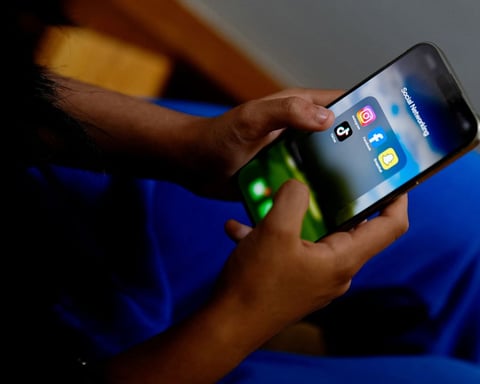 A high school student displays social media apps on a phone as Britain weighs a ban for under-16s
