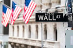 Wall Street street sign with American flags, as prediction exchange Kalshi rolls out employment verification to fight insider trading