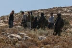 Israeli forces and armed settlers guard a bulldozer operating on Palestinian land near Dura, west of Hebron, in the occupied West Bank