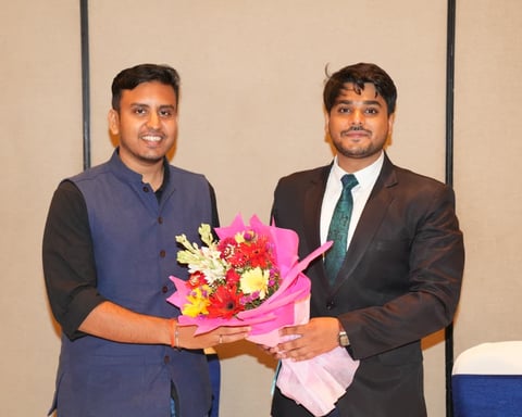 Two men in formal attire presenting a document at the Visvaniti Foundation 1st Annual Meeting in New Delhi