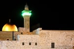 The golden Dome of the Rock and Al-Aqsa Mosque minaret illuminated at night in occupied Jerusalem
