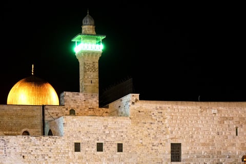 The golden Dome of the Rock and Al-Aqsa Mosque minaret illuminated at night in occupied Jerusalem