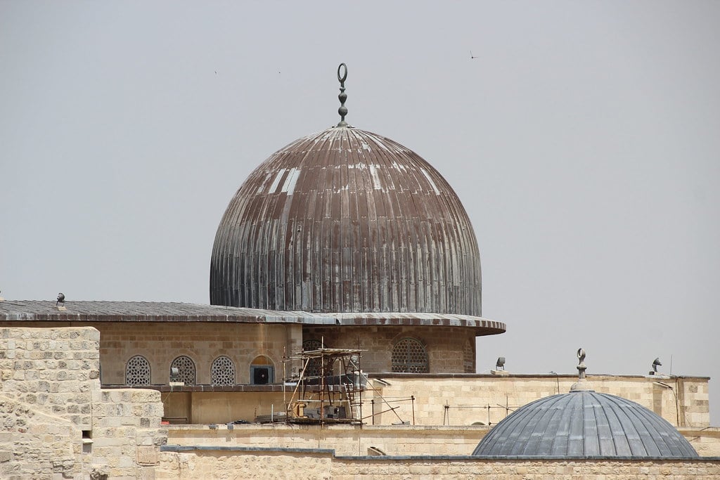 The silver dome of Al-Aqsa Mosque visible above stone walls in the Old City of occupied Jerusalem