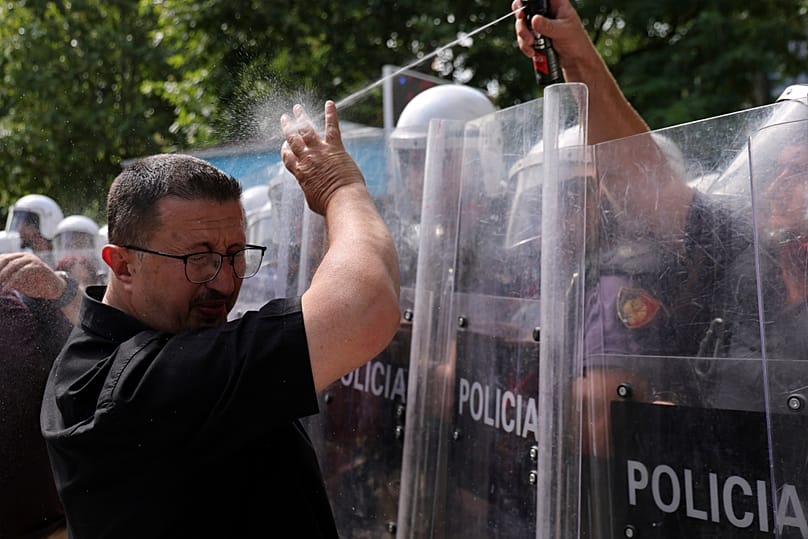 Albanian riot police officer uses pepper spray against a protester during clashes outside parliament in Tirana July 2026