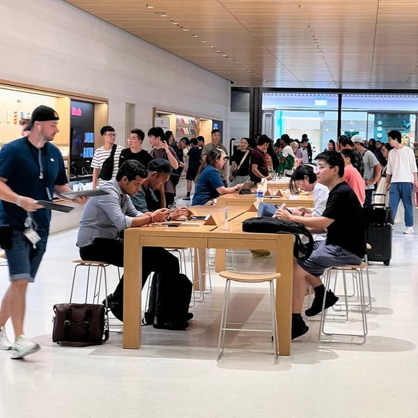 Customers using Apple devices inside an Apple retail store