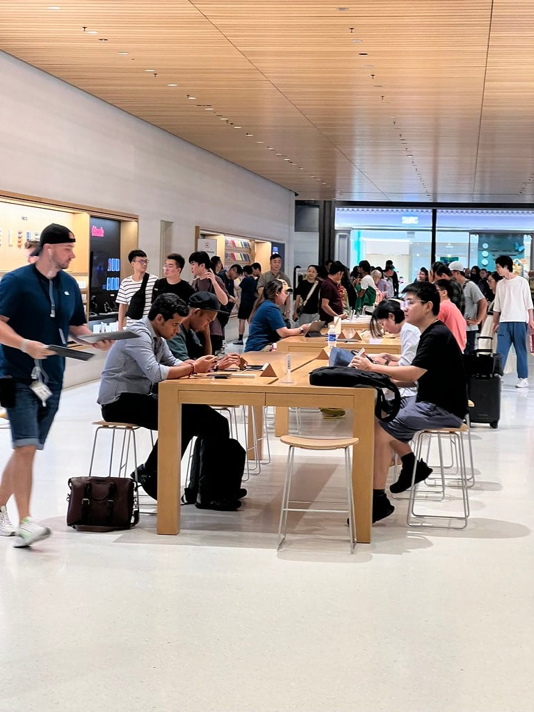 Customers using Apple devices inside an Apple retail store