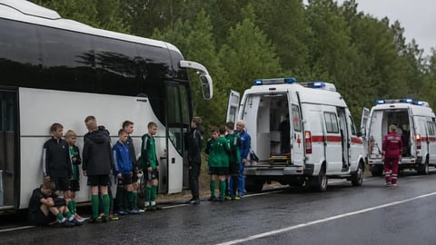 Belarusian youth football team players stand beside their bus with emergency services after drone strike in Bryansk region Russia June 2026