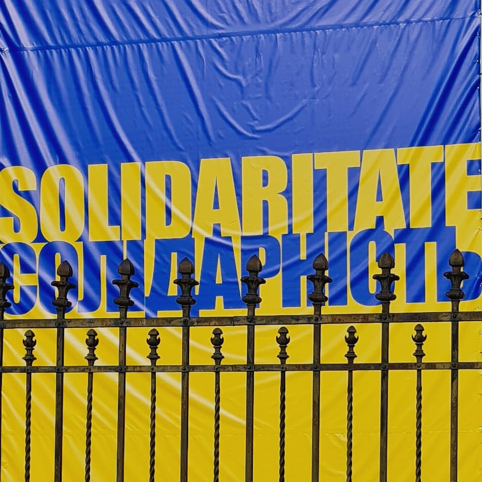 Protesters in Bucharest rally in solidarity with Ukraine holding flags and signs