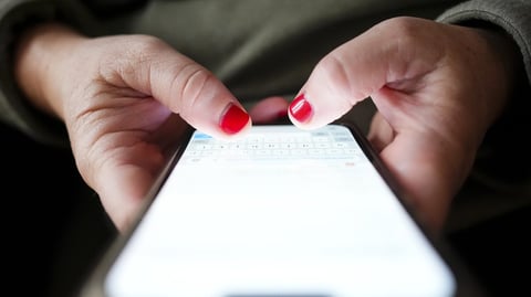 A person's hands typing on a smartphone, illustrating the Canadian wireless fee dispute