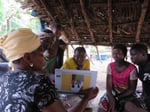 A community health worker demonstrates Ebola prevention techniques using educational materials in Congo