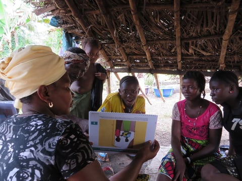 A community health worker demonstrates Ebola prevention techniques using educational materials in Congo