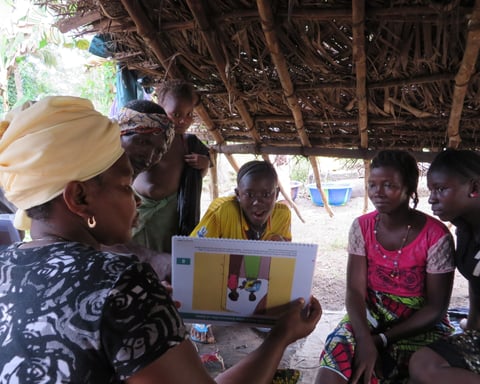 A community health worker demonstrates Ebola prevention techniques using educational materials in Congo