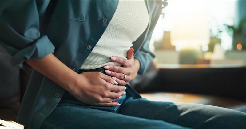 Woman holding her stomach in pain, illustrating cyclospora gastrointestinal symptoms affecting thousands of Americans