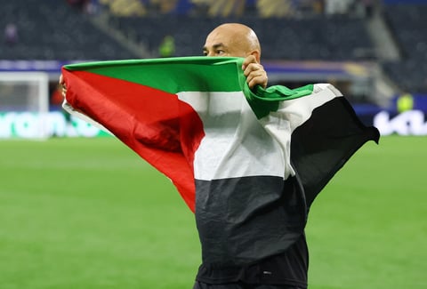 Egypt coach Hossam Hassan carries Egyptian and Palestinian flags onto the AT&T Stadium pitch after Egypt's historic World Cup knockout win over Australia