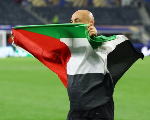 Egypt coach Hossam Hassan carries Egyptian and Palestinian flags onto the AT&T Stadium pitch after Egypt's historic World Cup knockout win over Australia
