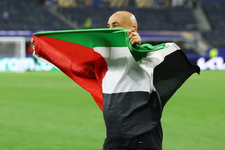 Egypt coach Hossam Hassan carries Egyptian and Palestinian flags onto the AT&T Stadium pitch after Egypt's historic World Cup knockout win over Australia