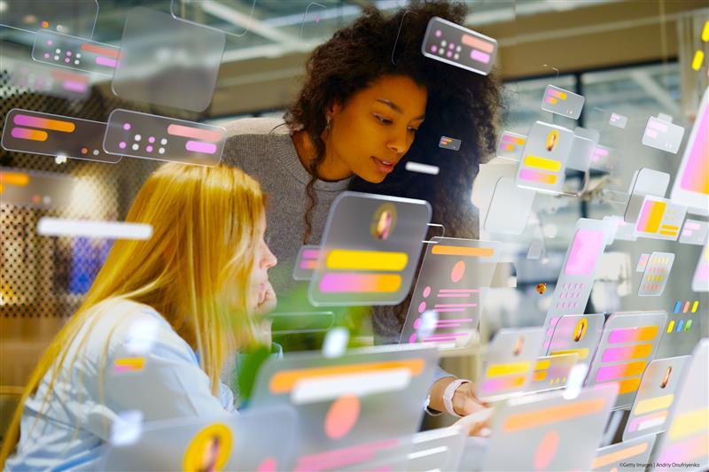 Young professionals working in a modern office surrounded by multicolored digital data screens illustrating AI systems in European institutions